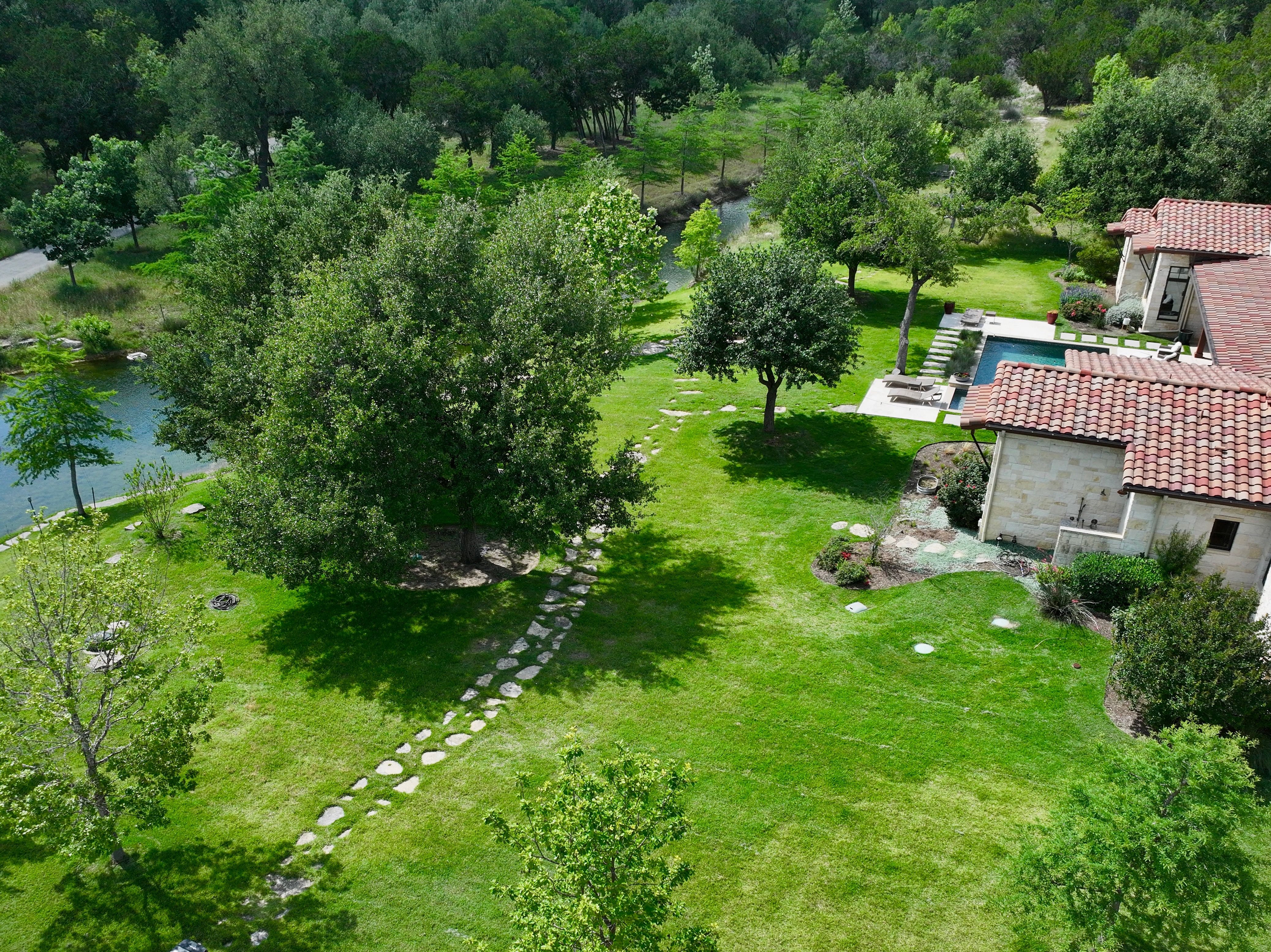 Aerial view of landscaped estate with stone pathways and pool completed by Aiden's Construction in Austin TX